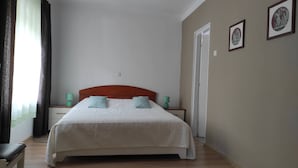 A neatly made bed with a wooden headboard, two bedside tables with green lamps, and a door to the right.