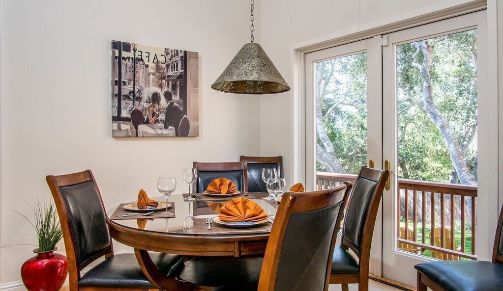 Un coin repas avec une table ronde, six chaises et un luminaire suspendu.
