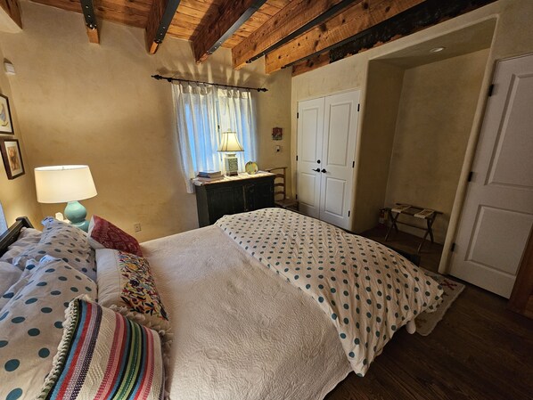 A bedroom with a bed, a nightstand, a lamp, a dresser, and a wardrobe.