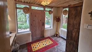 A wooden ceiling with a hanging light fixture, a wooden door, and a window with a view of greenery.
