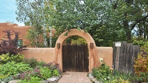 A gated entrance with a stone pathway leading to a building with a stucco exterior.