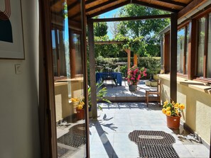 A covered outdoor patio with a table and chairs, surrounded by potted plants and a clear view of the garden. - Private heated pool,share with friend and family, full aircon secluded location. (Breuil-Barret)