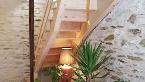 Ein rustikales Dachzimmer mit freiliegenden Holzbalken, geneigter Decke und einem kleinen Tisch mit Topfpflanzen.
