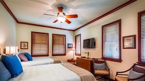 A hotel room with two beds, a desk, a chair, a ceiling fan, and large windows with blinds. - 2 BR rental with a nice tropical view - Hilton Waikoloa Access Included (Waikoloa)