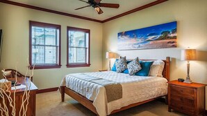 A bedroom with a bed, two windows, a ceiling fan, a nightstand, a lamp, and a painting on the wall.