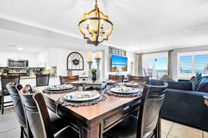 A modern kitchen with a dining area, a chandelier, and a view of the ocean.