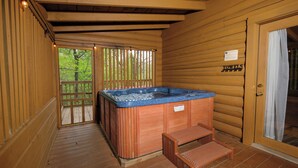 Une cabane en bois dotée d’un bain à remous, d’une terrasse en bois et d’un panneau indiquant que des serviettes sont à disposition.