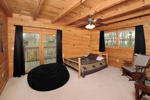 A wooden cabin room with a bed, a chair, a bean bag, and a ceiling fan. - 2 king bedrooms, hot tub, great location! (Sevierville)