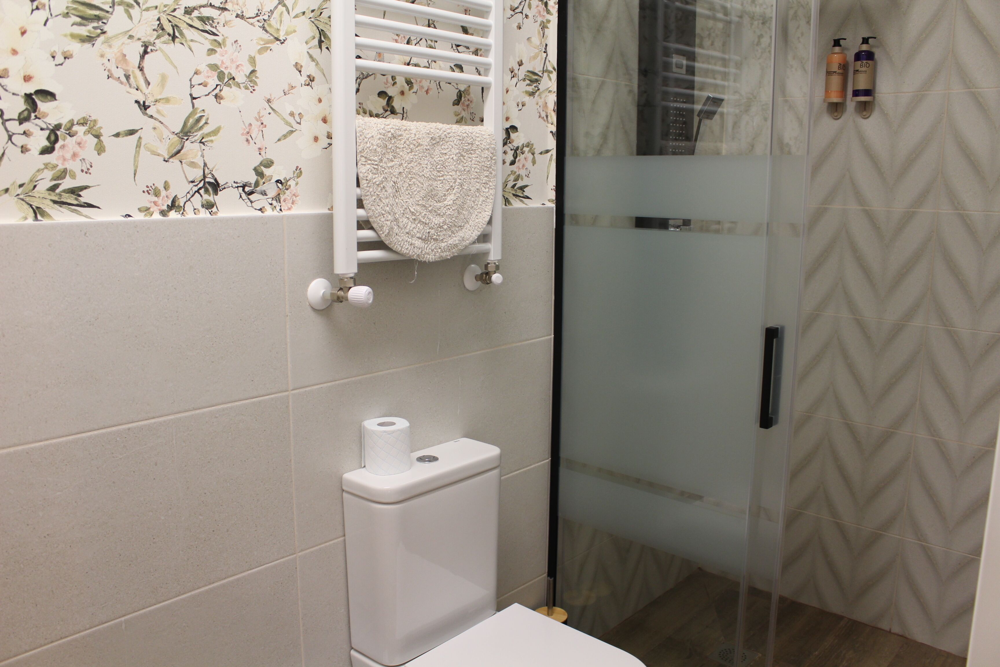 Un baño con inodoro, toallero y zona de ducha.