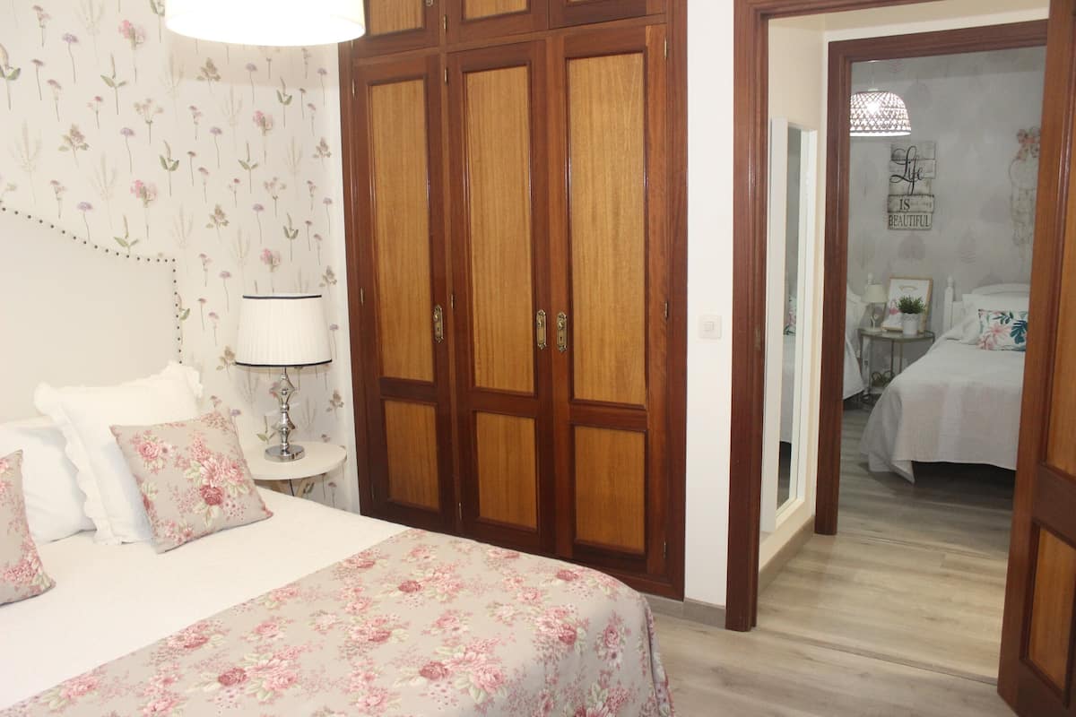 A bedroom with a bed, a nightstand, a lamp, and a wardrobe.