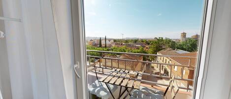 A balcony with a view of a town, including buildings and a tower.