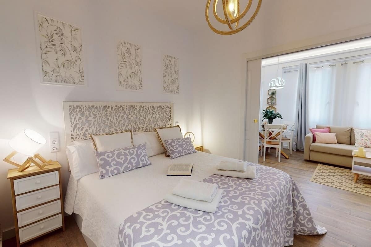 A bedroom with a bed, bedside tables, a desk, and a sofa.