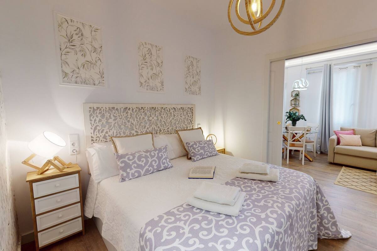 A modern bedroom with a large bed, bedside tables, a desk, and a sofa.