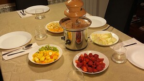 Une table à manger dressée pour un repas, avec des assiettes, des couverts et un récipient à fondue.