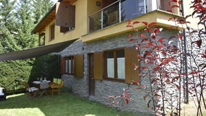 Une maison à deux étages avec une façade en pierre, des volets en bois et un balcon.