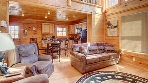 A cabin interior with a dining area, kitchen, and seating area. - Pool table, hot tub, 2 bedroom log cabin close to Dollywood and National Park! (Sevierville)