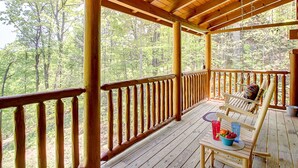 A wooden deck with a view of a forest. - Pool table, hot tub, 2 bedroom log cabin close to Dollywood and National Park! (Sevierville)
