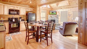 A wooden cabin interior with a kitchen, dining area, and a fireplace. - Pool table, hot tub, 2 bedroom log cabin close to Dollywood and National Park! (Sevierville)