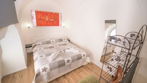 Una camera da letto con un letto, un quadro appeso al muro, una rastrelliera in metallo e una sedia di legno.