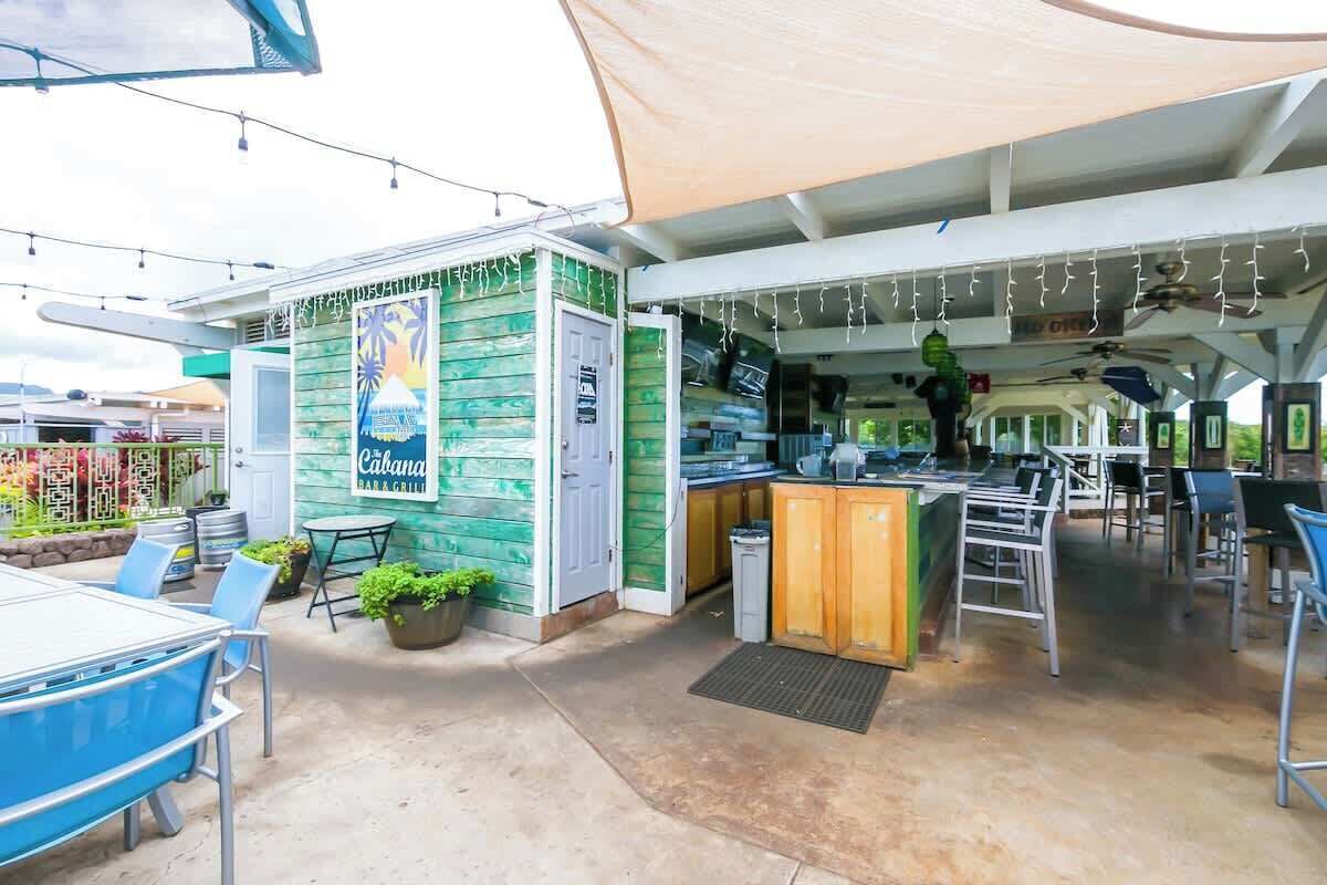 Ein Außenbereich mit Bar und Grill, eine grüne Fassade, Sitzgelegenheiten im Freien und eine Theke mit Barbekleidung.