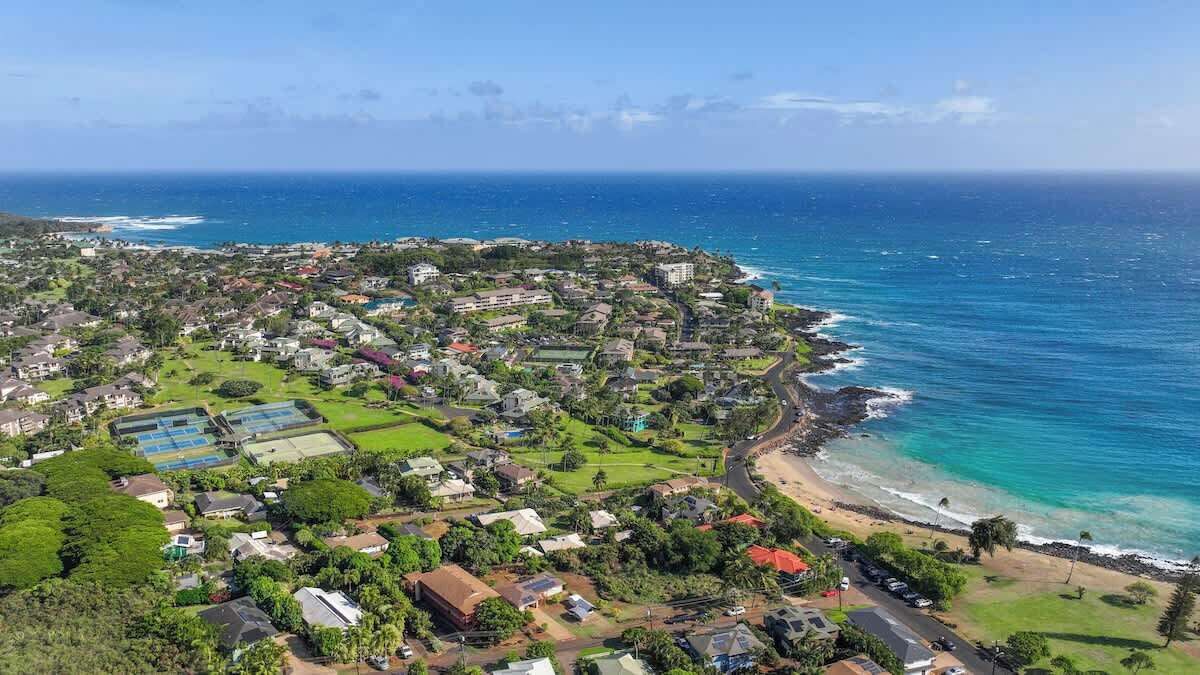 A coastal town with residential buildings, a beach, and a clear view of the ocean.