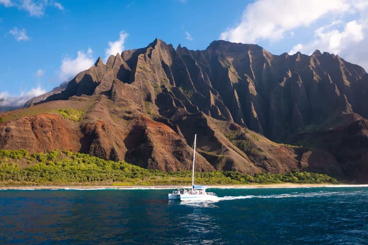 Um barco em um mar azul e límpido, com montanhas ao fundo.