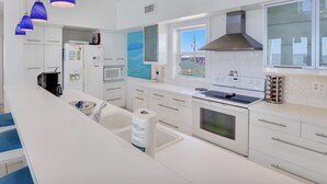 Een moderne keuken met witte kasten, een ingebouwde oven, een magnetron en een groot raam.