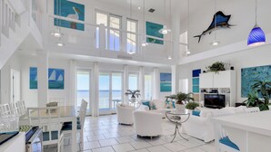 Een ruime woonkamer met balkon, witte meubels en kunstwerken met afbeeldingen van zeedieren.