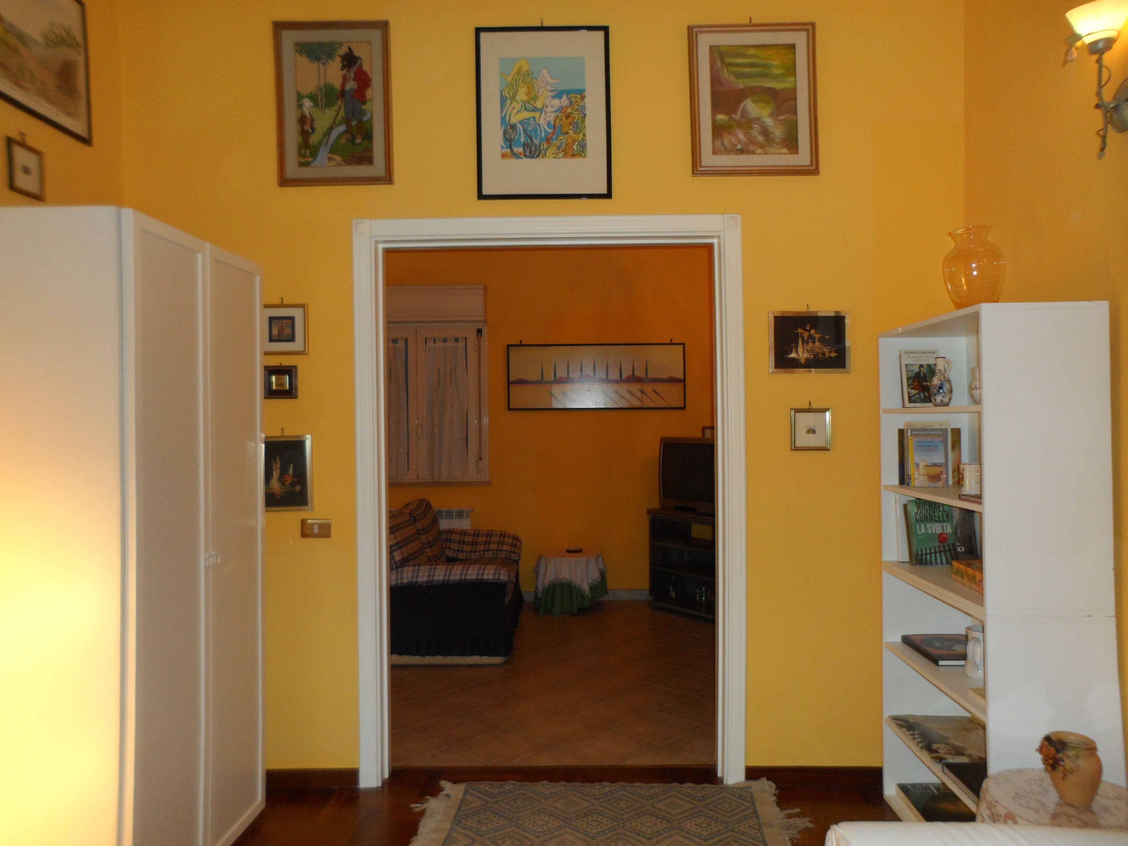 Una stanza con un letto, una televisione e una libreria.