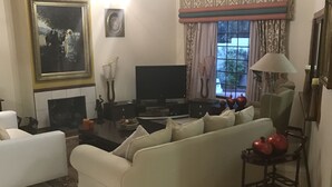 Un salon avec un canapé, un téléviseur, une cheminée et une fenêtre avec des rideaux.