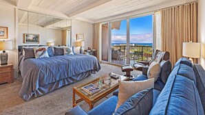 Une chambre d’hôtel spacieuse, dotée d’un grand lit, d’un canapé, d’une table basse et d’un balcon avec vue.