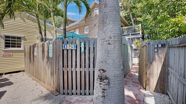 A wooden fence with a mailbox and a recycling bin. - **THE MELLOW MACAW** Cozy Condo Near Duval + Last Key White Glove Service... (Key West)