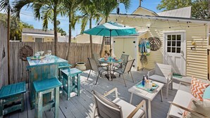 A patio with outdoor furniture, a table with drinks, and a decorative umbrella. - **THE MELLOW MACAW** Cozy Condo Near Duval + Last Key White Glove Service... (Key West)