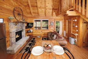Cozy cabin interior with a stone fireplace, dining table, and comfortable seating area.