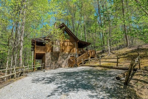 Escape to a secluded cabin surrounded by lush forest, with a balcony and staircase leading to an upper level.