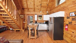 A wooden cabin interior with a kitchen, dining area, and a staircase. - POOL TABLE, HOT TUB, AND JACUZZI TUB in a CONVENIENT location! (Sevierville)