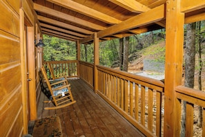 Enjoy a peaceful retreat on the deck with a forest view, featuring a comfortable rocking chair and a warm welcome.