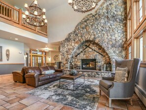 A spacious living area with a stone fireplace, leather sofas, and a chandelier.