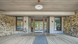 A covered porch with a stone wall, wooden flooring, and a bicycle parked to the side. - Bright Corner Unit in River Run/Walk to the Slopes/Pool and Hot Tub Access (Keystone)