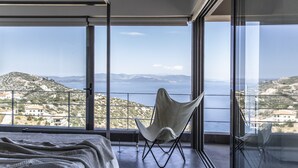 A bedroom with a large window, a bed, and a chair. - Sea View Villa Schinias (Marathon)