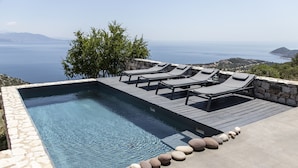 A rectangular infinity pool with lounge chairs and a stone border. - Sea View Villa Schinias (Marathon)