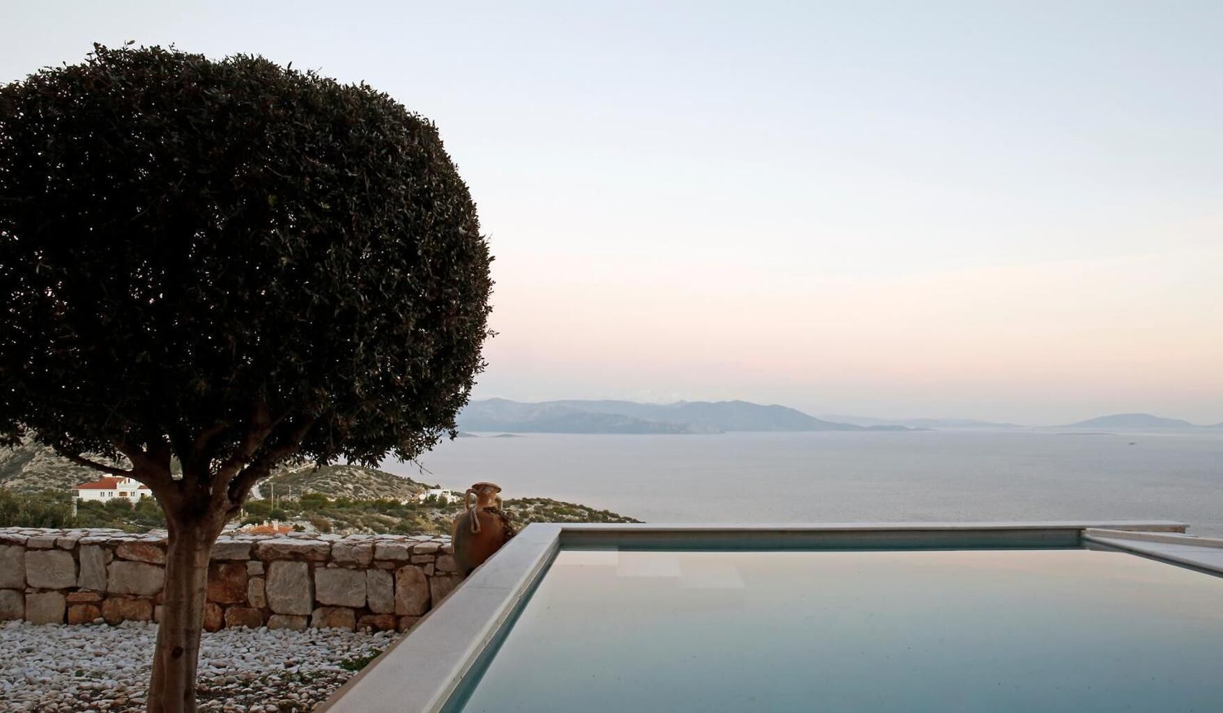 A pool with a view of the sea and mountains.