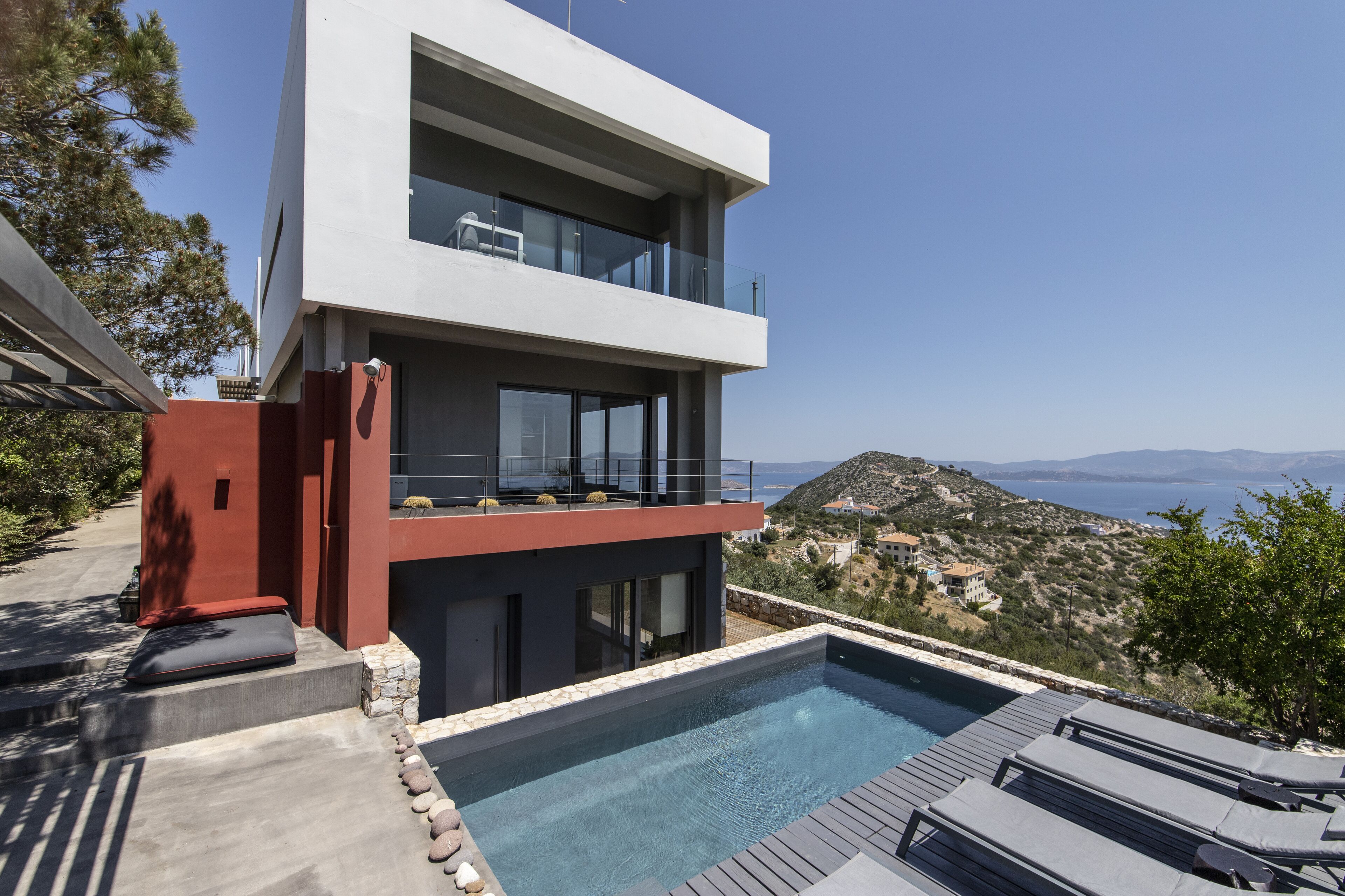 A modern two-story house with a rooftop pool and a scenic view of the sea.
