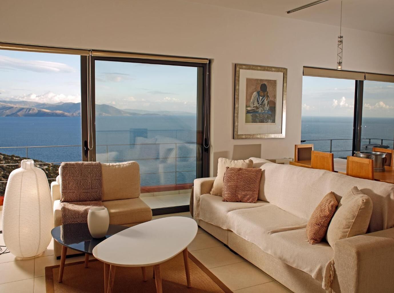 Ein modernes Wohnzimmer mit einer großen Couch, einem Couchtisch und Blick auf das Meer.