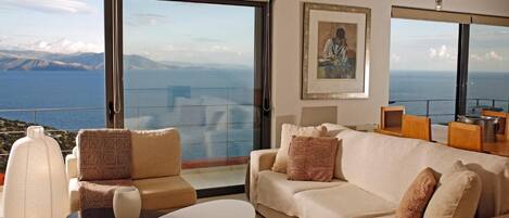 Un salon moderne avec un grand canapé, une table basse et une vue sur la mer.