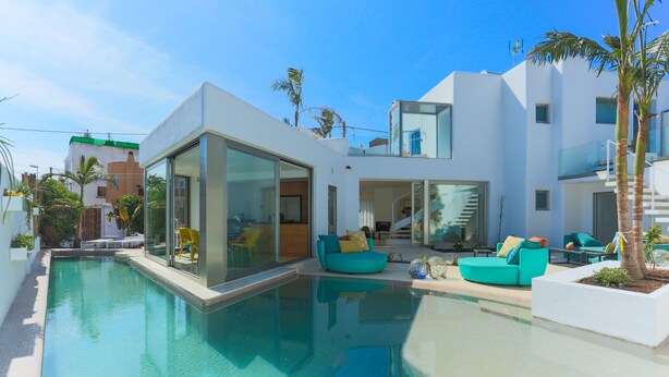 A modern pool area with a glass-enclosed pool, turquoise outdoor furniture, and a staircase leading to an upper level. - BEAUTIFUL VILLA IN THE HEART OF Playa den Bossa<br>ETV-2047-E (Playa den bossa, San jordi de ses Salines, IBIZA)