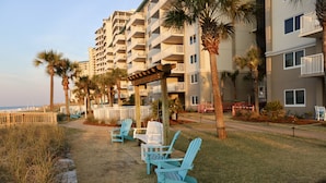 Una propiedad frente a la playa con un patio que cuenta con sillas tipo Adirondack y un pergolado de madera.