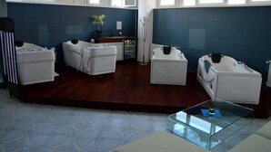 Een moderne badkamer met drie witte badkuipen, een glazen bijzettafeltje en een wand betegeld met blauwe tegels.