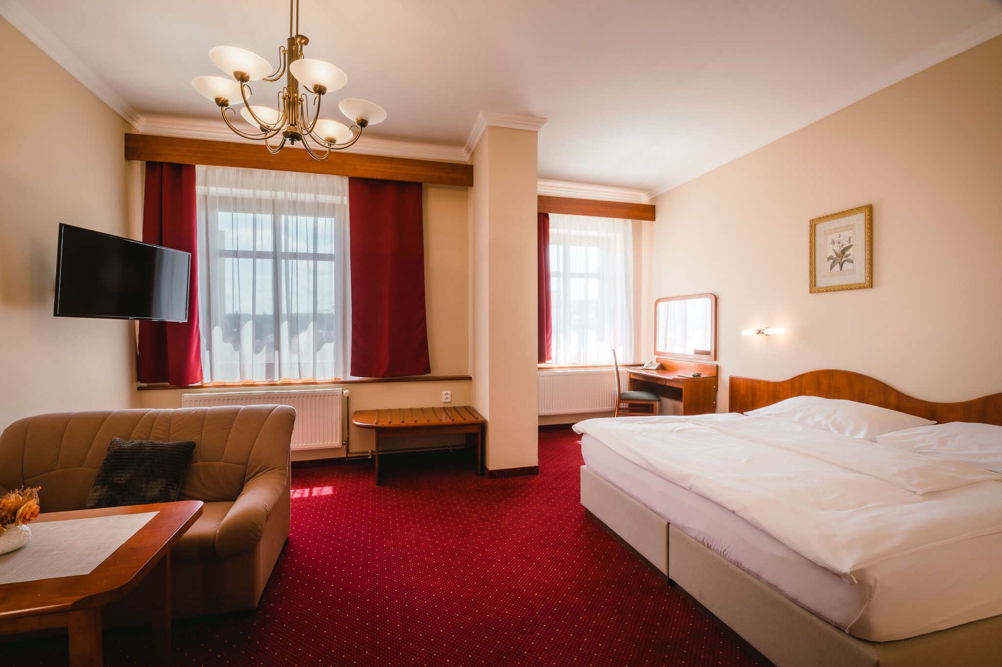 A hotel room with a bed, a desk, a chair, a television, and a window with curtains.
