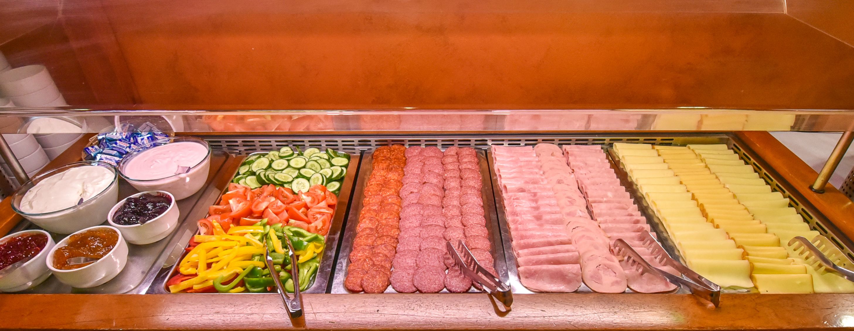 A buffet with various food items including sliced vegetables, meats, and dips.